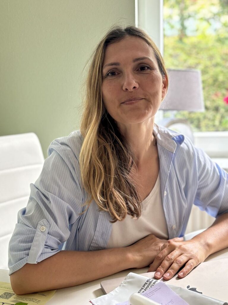 Anja Feierabend lächelt am Schreibtisch ihrer Naturheilpraxis in Kronberg