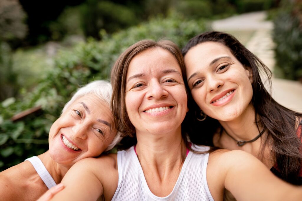Drei Frauen unterschiedlichen Alters lachen gemeinsam in die Kamera